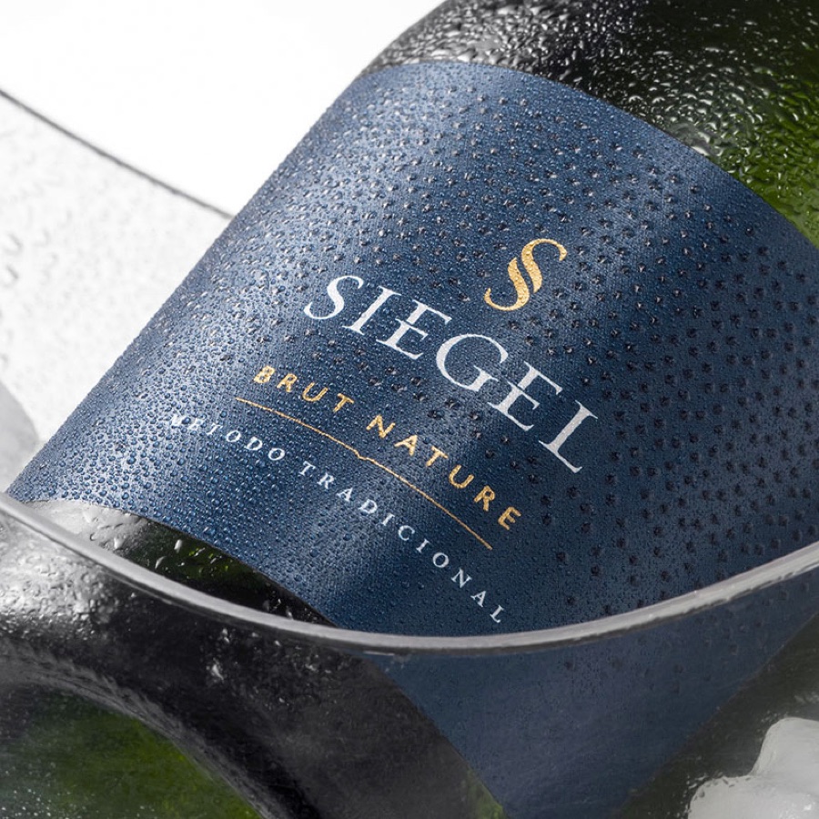 Etiqueta azul con folia dorada de Siegel Brut Nature, mojada en hielo